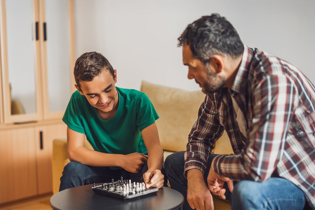 male-teenager-playing-chess-with-elder-male