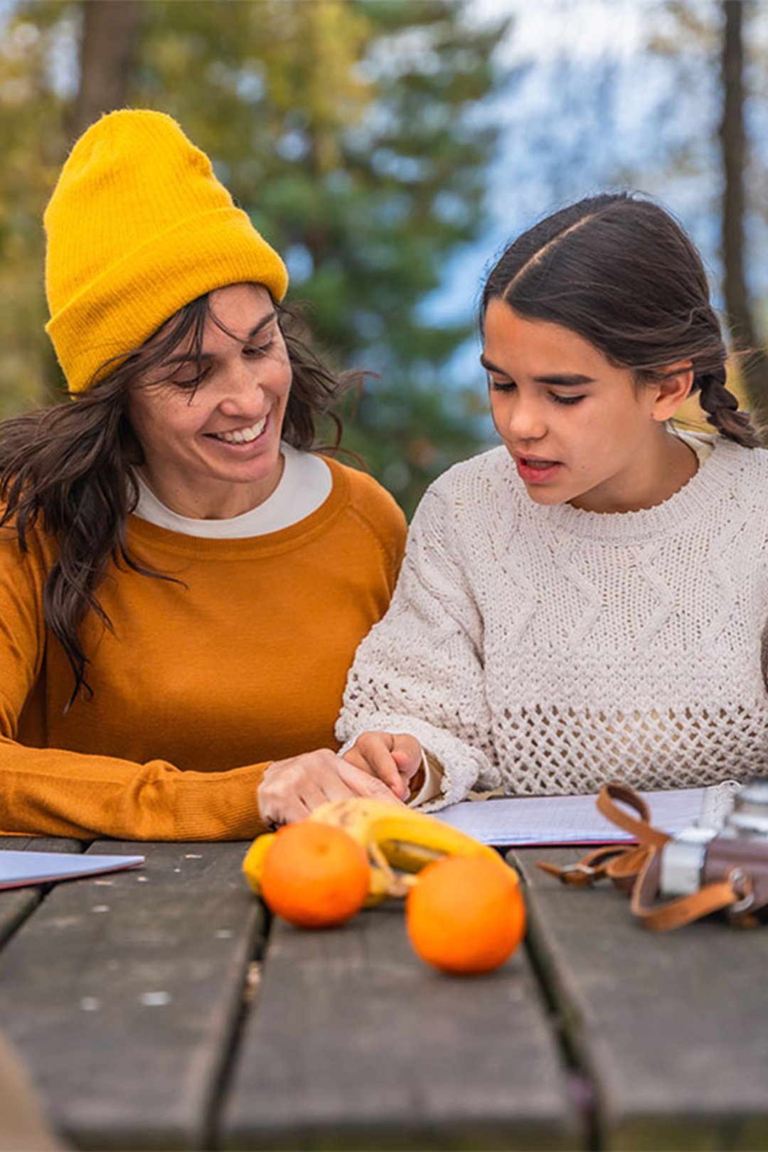 woman-helping-teenage-girls-with-school-project-at-park-VERTICAL